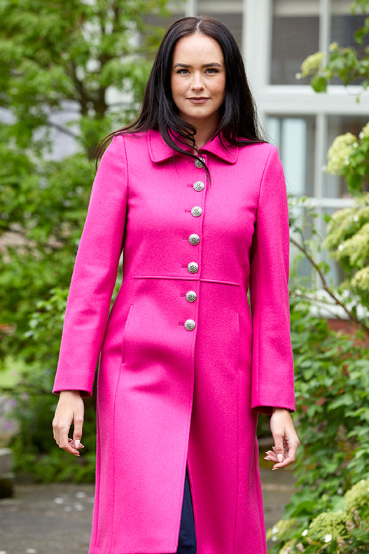 Model wearing a pure wool bright pink , single breasted coat with silver buttons