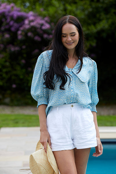 Model wearing a pale blue print blouse with oversized collar