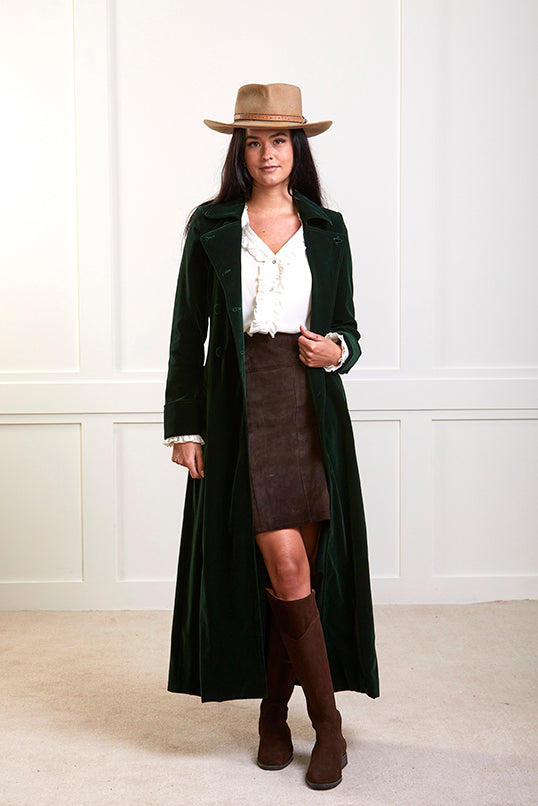 Model wearing a long green velvet coat with green velvet buttons