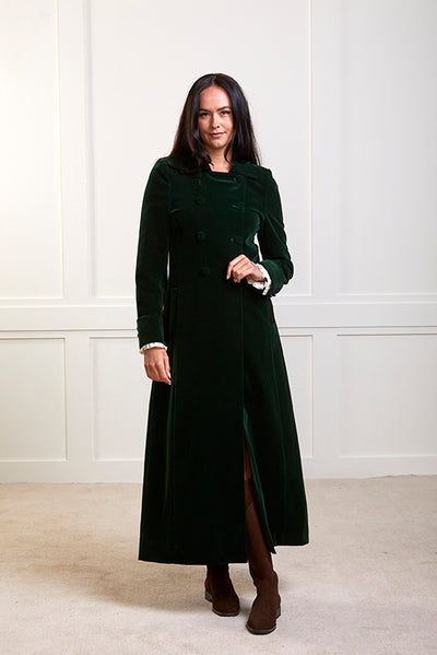 Model wearing a long green velvet coat with green velvet buttons