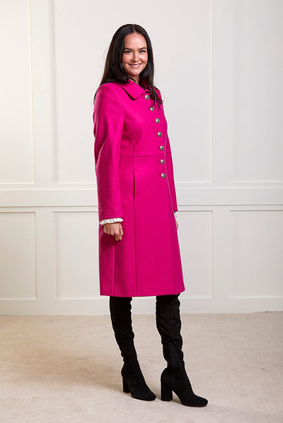 Model wearing a pure wool bright pink , single breasted coat with silver buttons