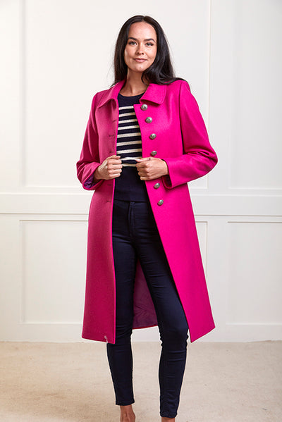 Model wearing a pure wool bright pink , single breasted coat with silver buttons