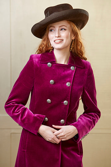 Women's long pink velvet coat with military style silver buttons.