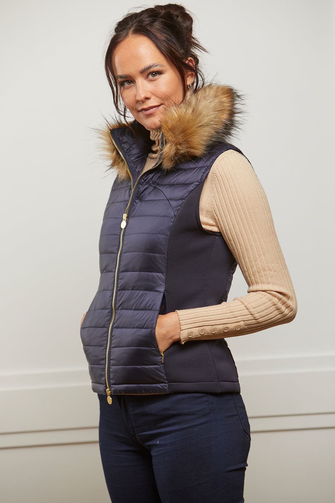 Women's navy puffer gilet with detachable faux fur collar and branded gold zip