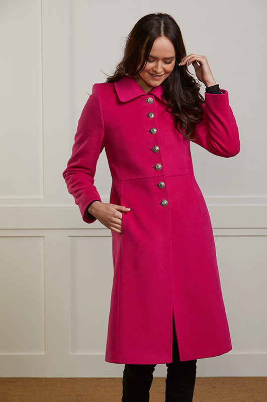 Model wearing a women's winter coat in vibrant pink cashmere and wool blend. The coat is single breasted and has 7 military style buttons to the front.