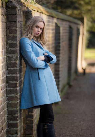 Model wearing a pale blue coat in pure wool with navy velvet trims.